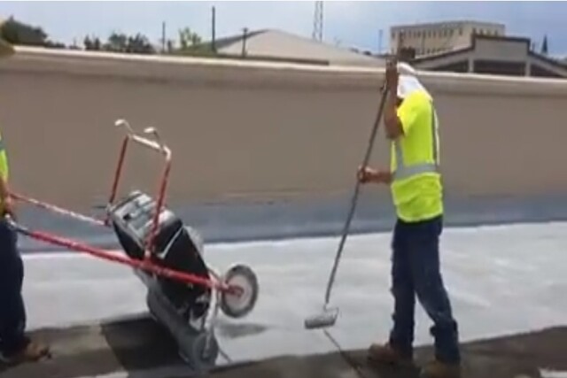 Roofing worker applying urethane for leak on commercial flat roof