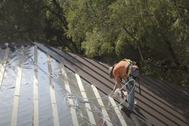 Roofing worker installing metal roof on the house