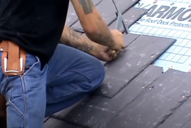 Roofing worker installing slate tile roof